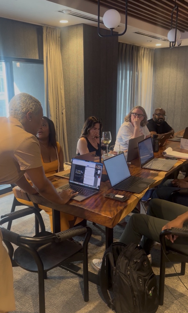 Karima Williams teaching a small group gathered around a table with their laptops